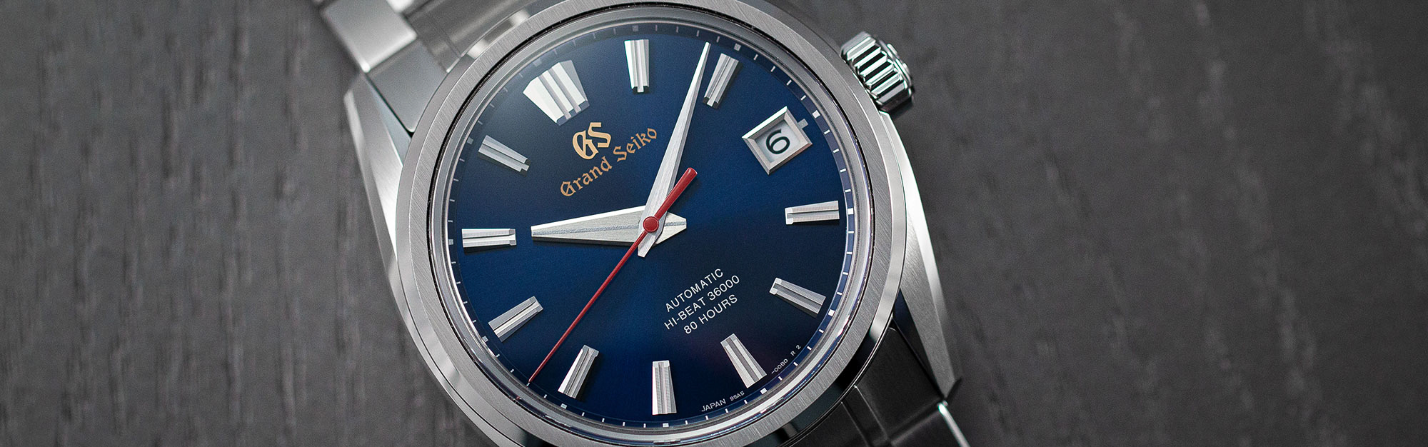 Grand Seiko SLGH003 wristwatch with a blue dial and red accents on a tabletop.